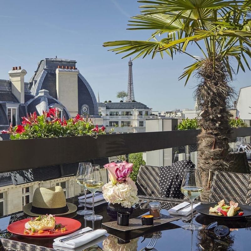 Dining tables arranged on a balcony overlooking the Eiffel Tower from Warwick Paris Champs Elysées