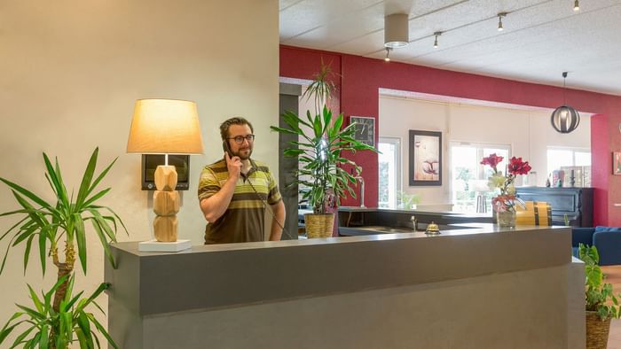 A receptionist at the reception desk in Hotel Aster
