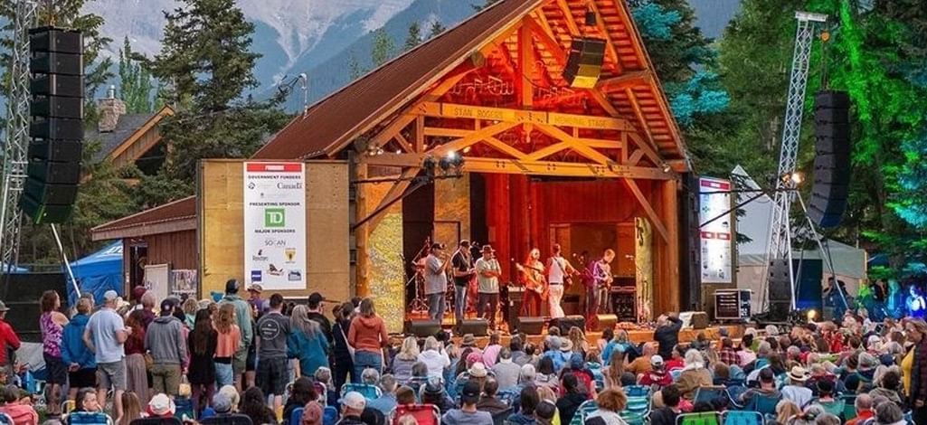 A large group of people watch a band perform outdoors