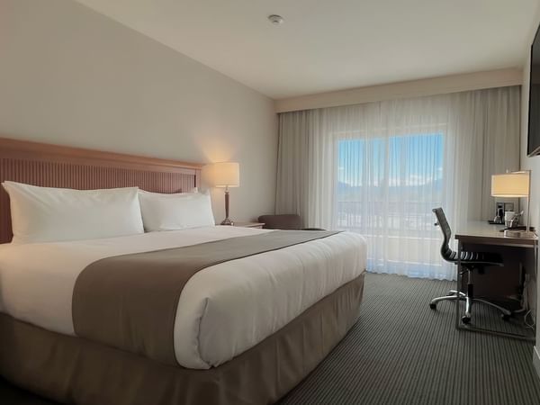 Guest room with king bed, tv, desk, chairs, window