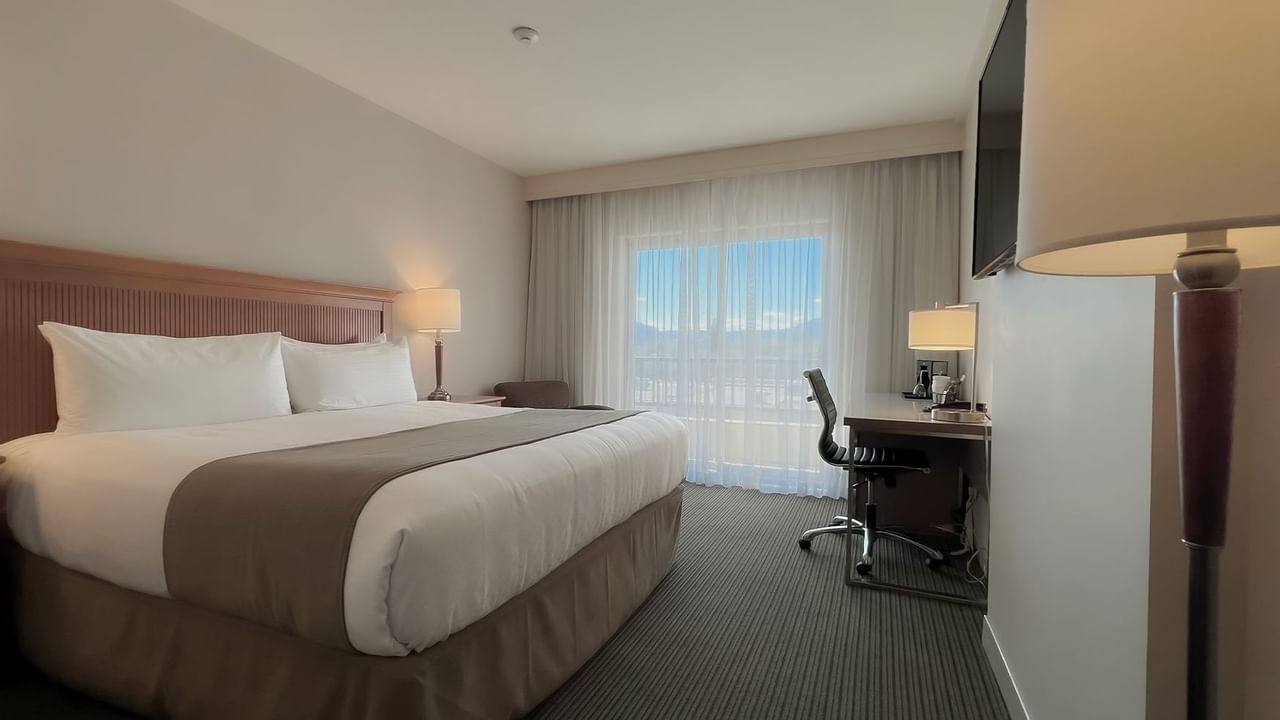 Guest room with king bed, tv, desk, chairs, window