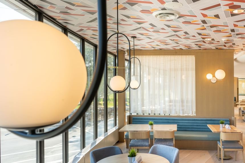Modern dining area at The Cannery Restaurant with geometric ceiling, large windows, wooden tables, and cushioned bench