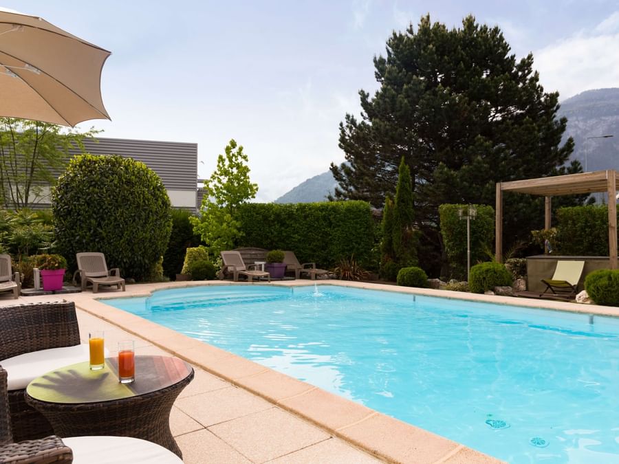 Lounge area by an outdoor swimming pool at Hotel du Faucigny