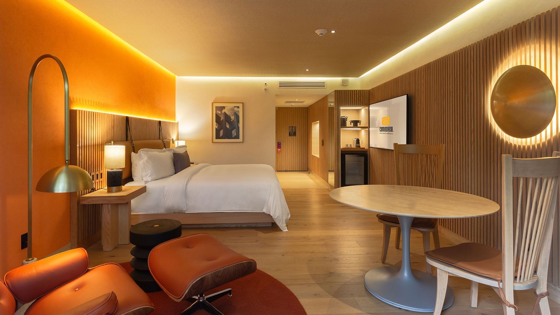 Habitación King Superior Camino Real Club con vista al jardín, pared naranja y sillón en Camino Real Polanco México