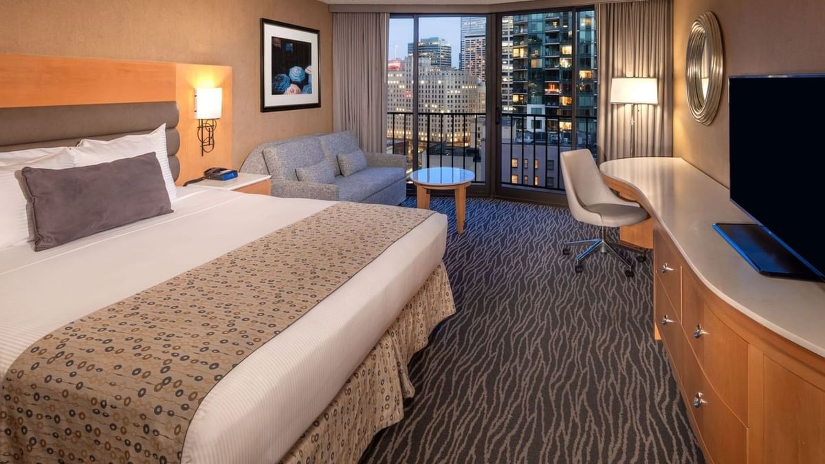 Accessible Premier Room featuring a grey sofa by a wooden desk under a round mirror at Warwick Seattle