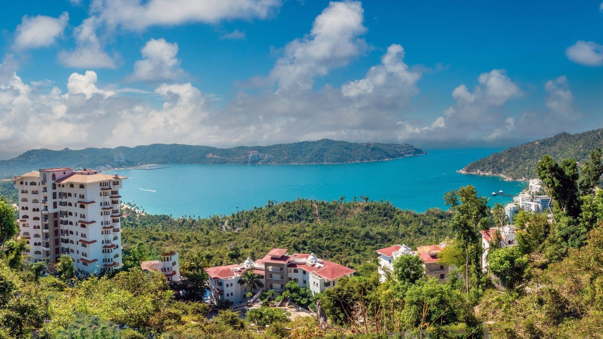 Aerial view of Bahía de Puerto Marqués, surrounded by lush green hills near Camino Real Acapulco Diamante