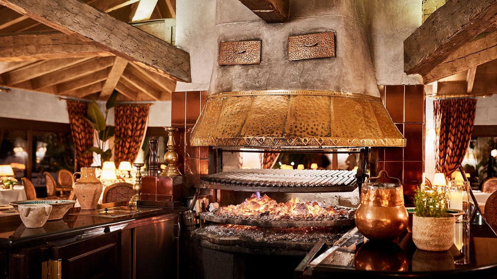 Large indoor copper grill and stone fireplace with glowing embers at Marbella Club