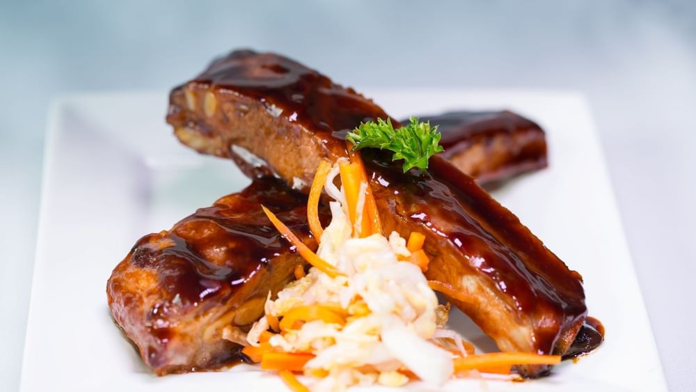 BBQ ribs by a pile of fresh coleslaw under a small parsley leaf in Tings on a Stick at Warwick Paradise Island Bahamas