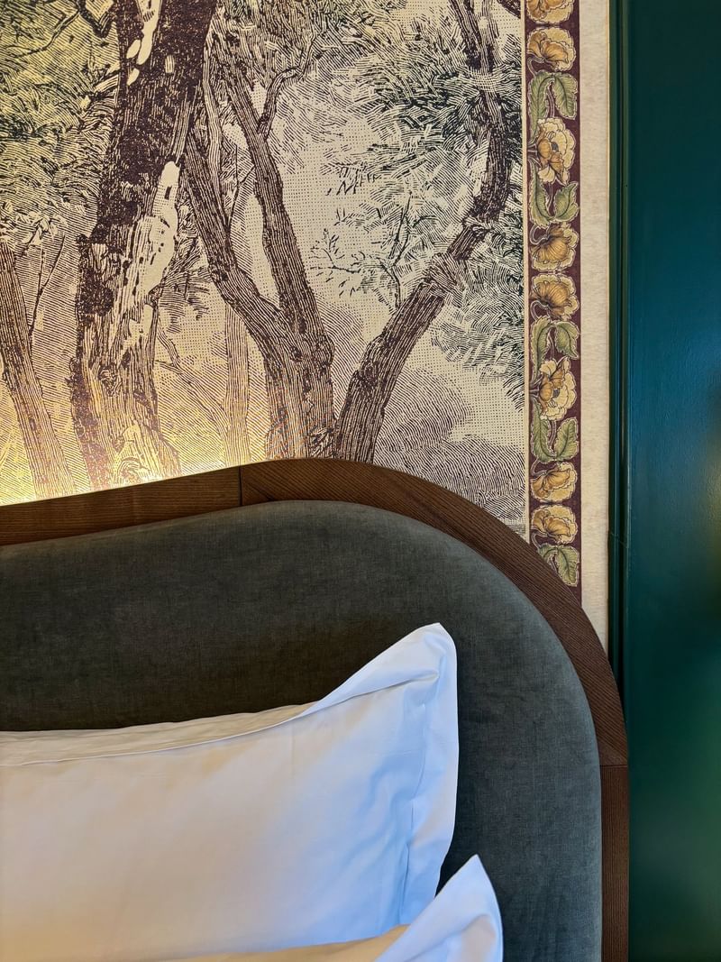 Executive Room bed with white pillows and floral print wall at The Capital Hotel, Apartments & Townhouse