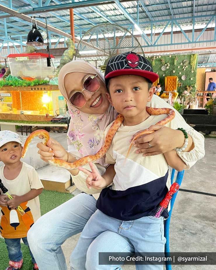 A woman and her sons were taking a picture with a snake at Pavilion Petting Zoo - Lexis Suites Penang