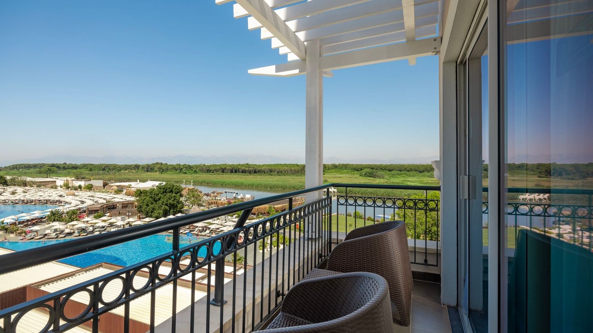 Balcony view with chairs overlooking a river in Riverside Room at Titanic Deluxe Golf Belek
