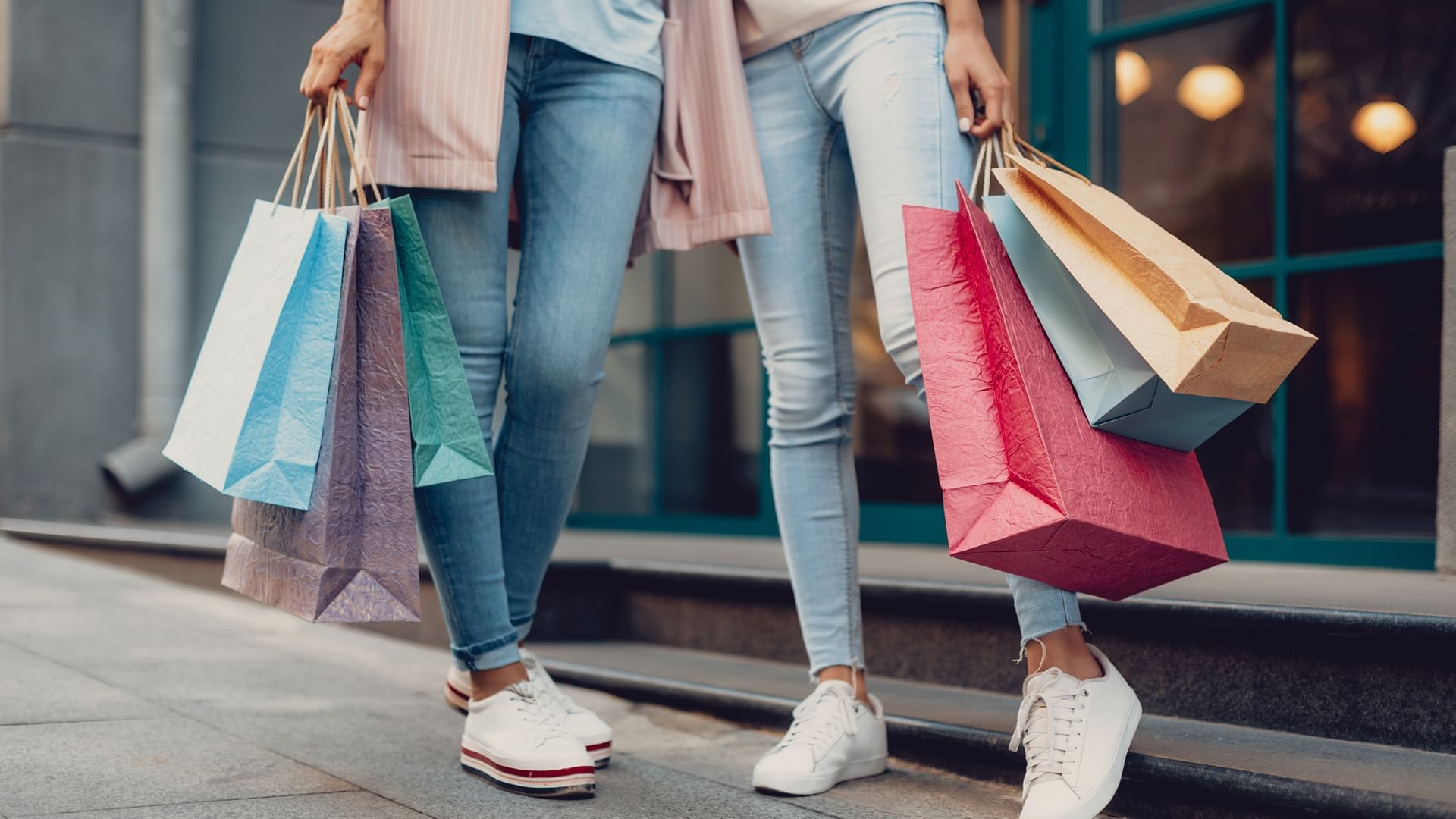 Ladies holding colorful shopping bags near Village Hotels