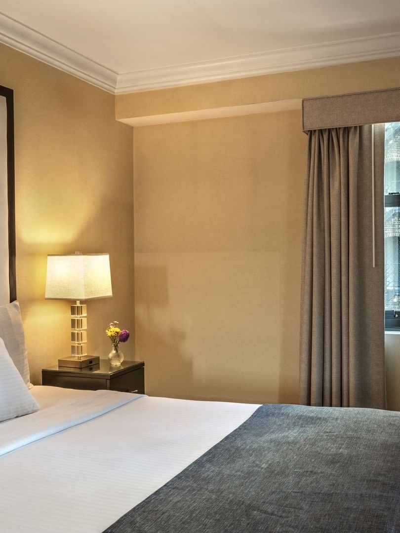 Bed with table lamp on side table near window in Superior Suite at Warwick Allerton Chicago