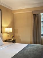 Bed with table lamp on side table near window in Superior Suite at Warwick Allerton Chicago