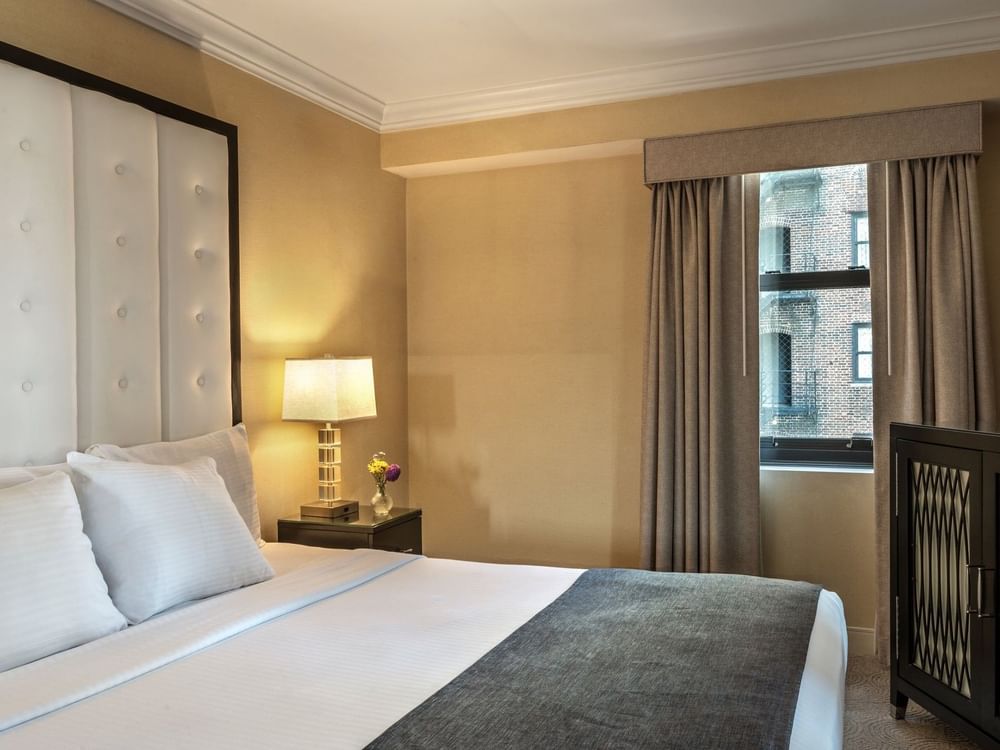 Bed with a side table near the window in Superior Suite at Warwick Allerton Chicago