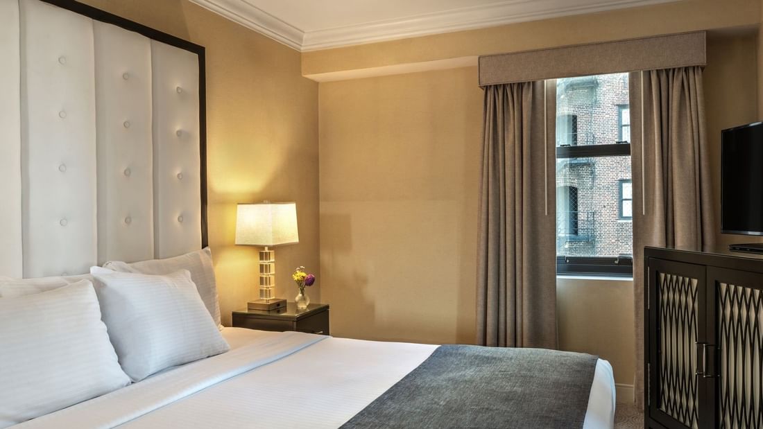 Bed with a side table near the window in Superior Suite at Warwick Allerton Chicago