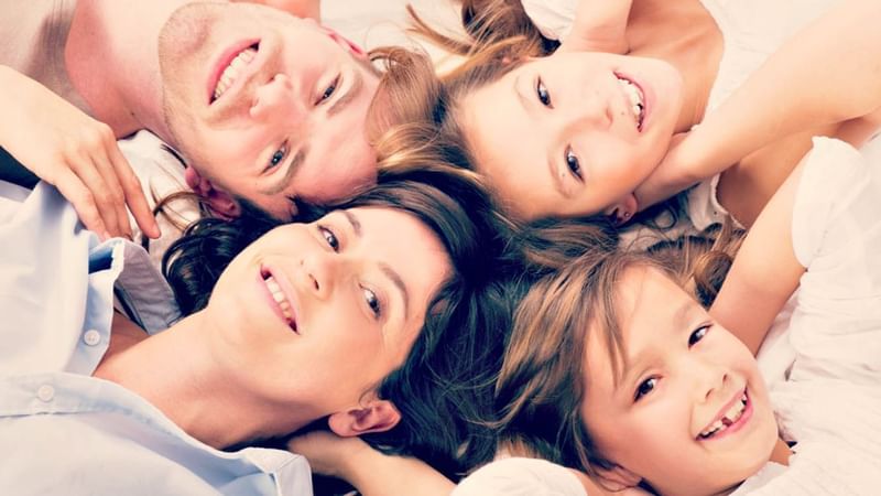 Headshot of a family laying down on a bed at Warwick Geneva