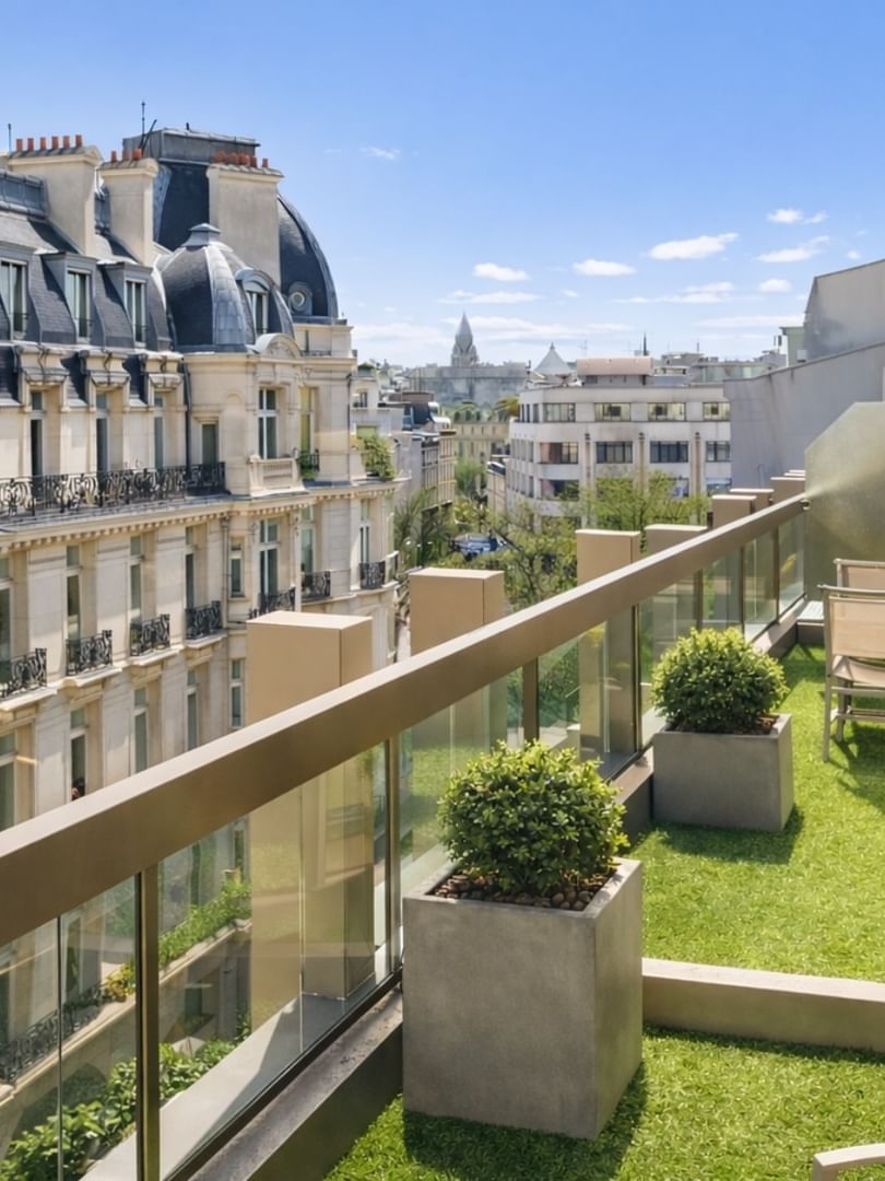 Outdoor chairs by potted plants on a green turf balcony in The Champs-Élysées Suite at Warwick Paris Champs Elysées
