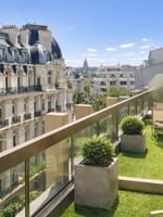 Outdoor chairs by potted plants on a green turf balcony in The Champs-Élysées Suite at Warwick Paris Champs Elysées