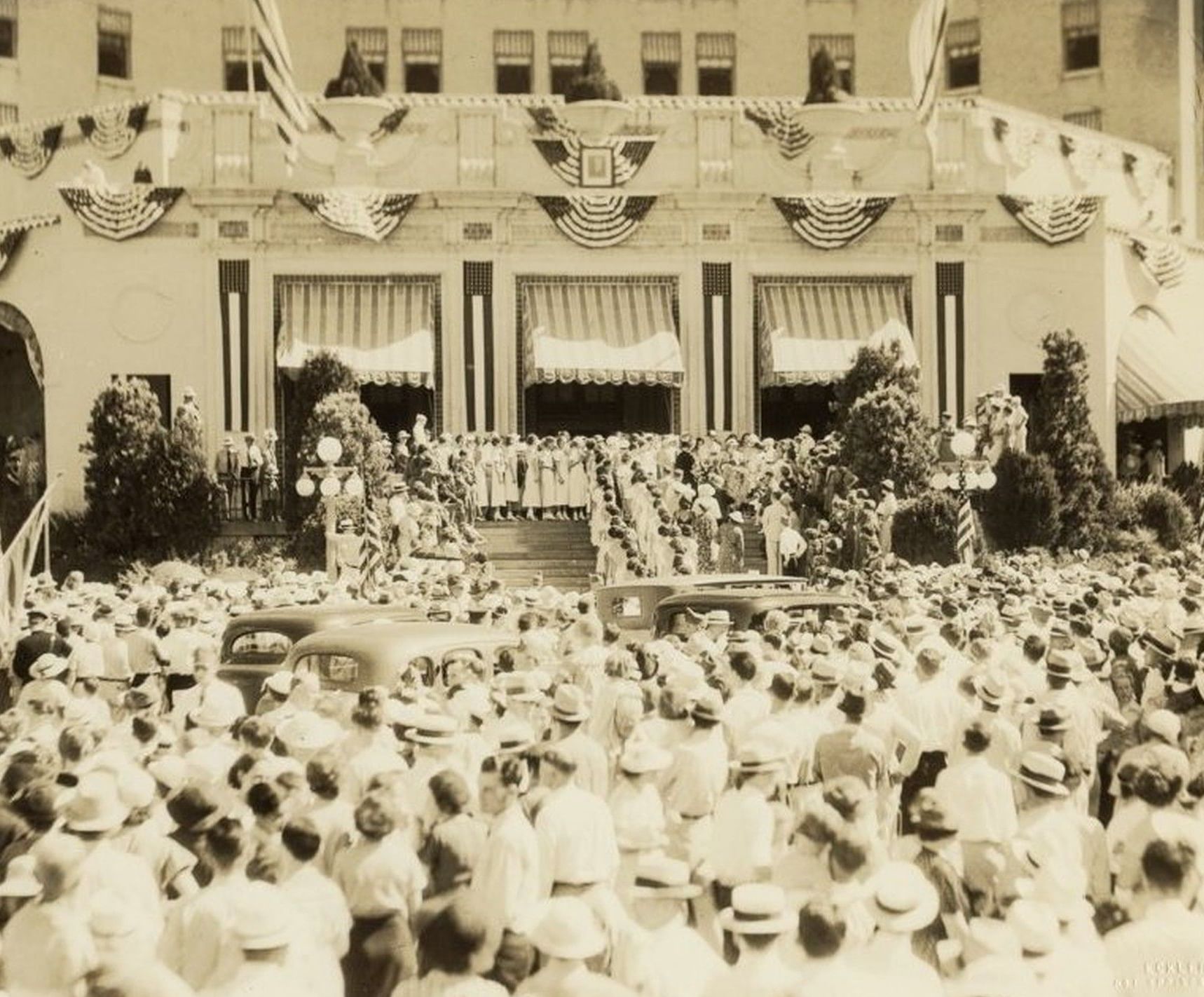 Vintage image of crowds and cars surrounding a decorated front entrance beneath awnings at Arlington Resort Hotel & Spa