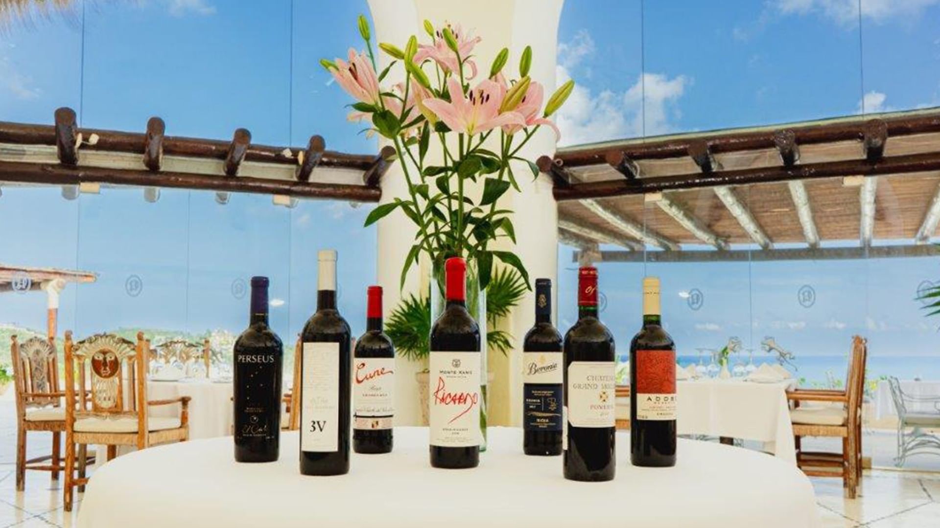 Wine display in Tierra Mia restaurant featuring dark bottles, under a glass wall at Quinta Real Huatulco