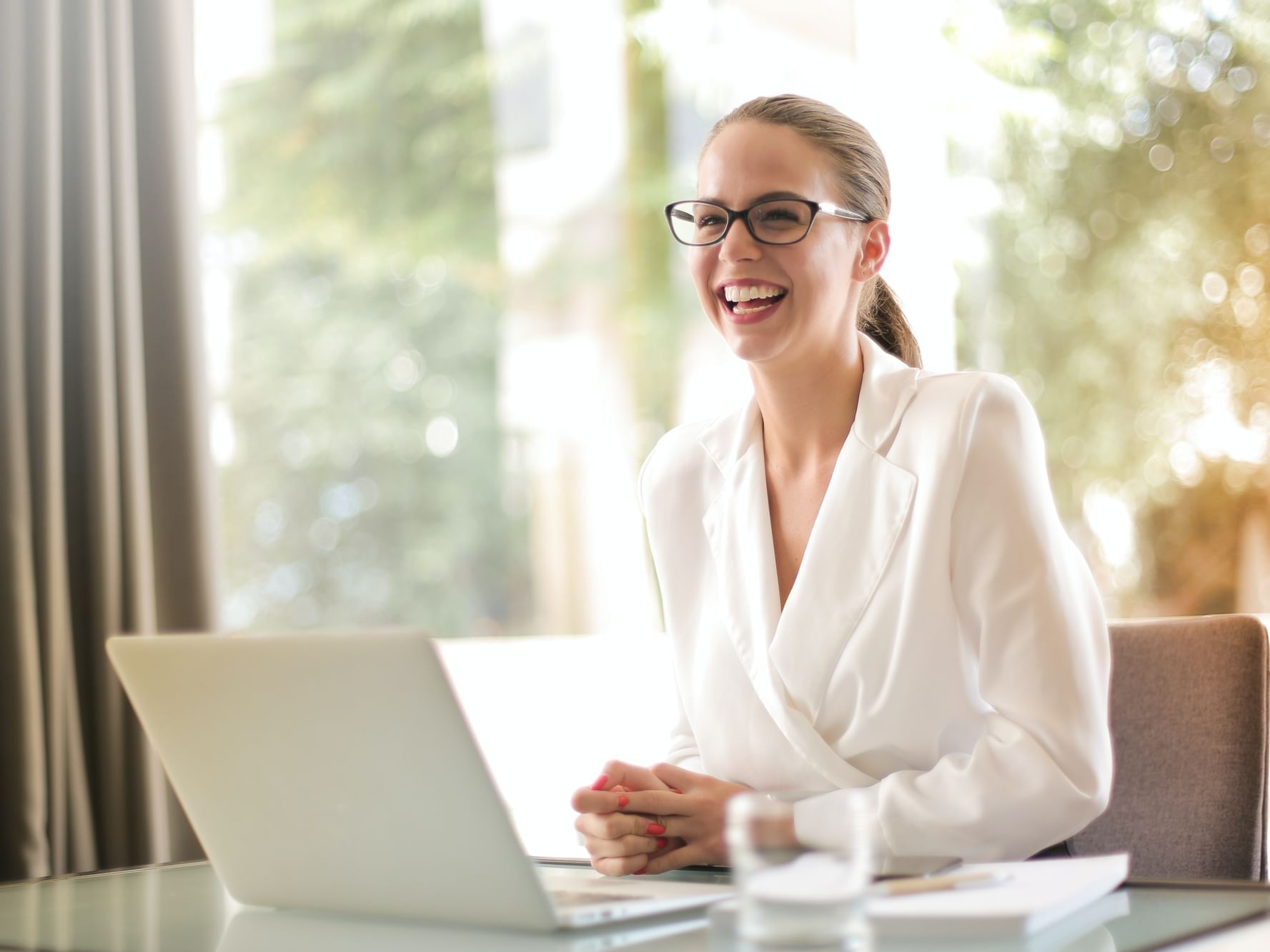Woman smiling while working on a laptop at City Seasons Hotels