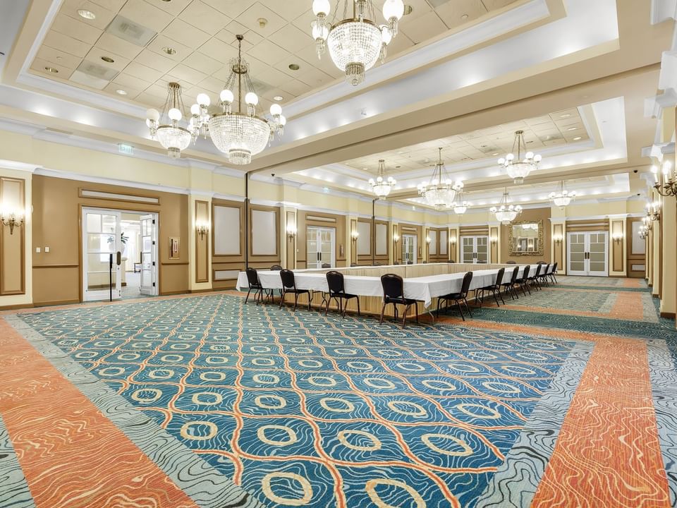 Poinsettia Ballroom featuring chandeliers, a large table with chairs, & colorful patterned carpet at El Conquistador Resort