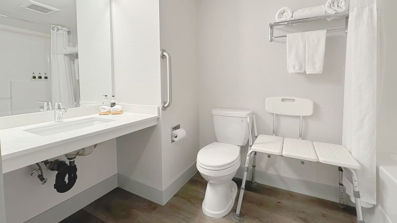 Accessible washroom with toilet, bathtub, soap, sink and towel