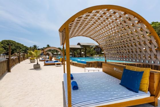 Beachside wooden bed adorned with blue pillows at Hotel Isla Del Encanto