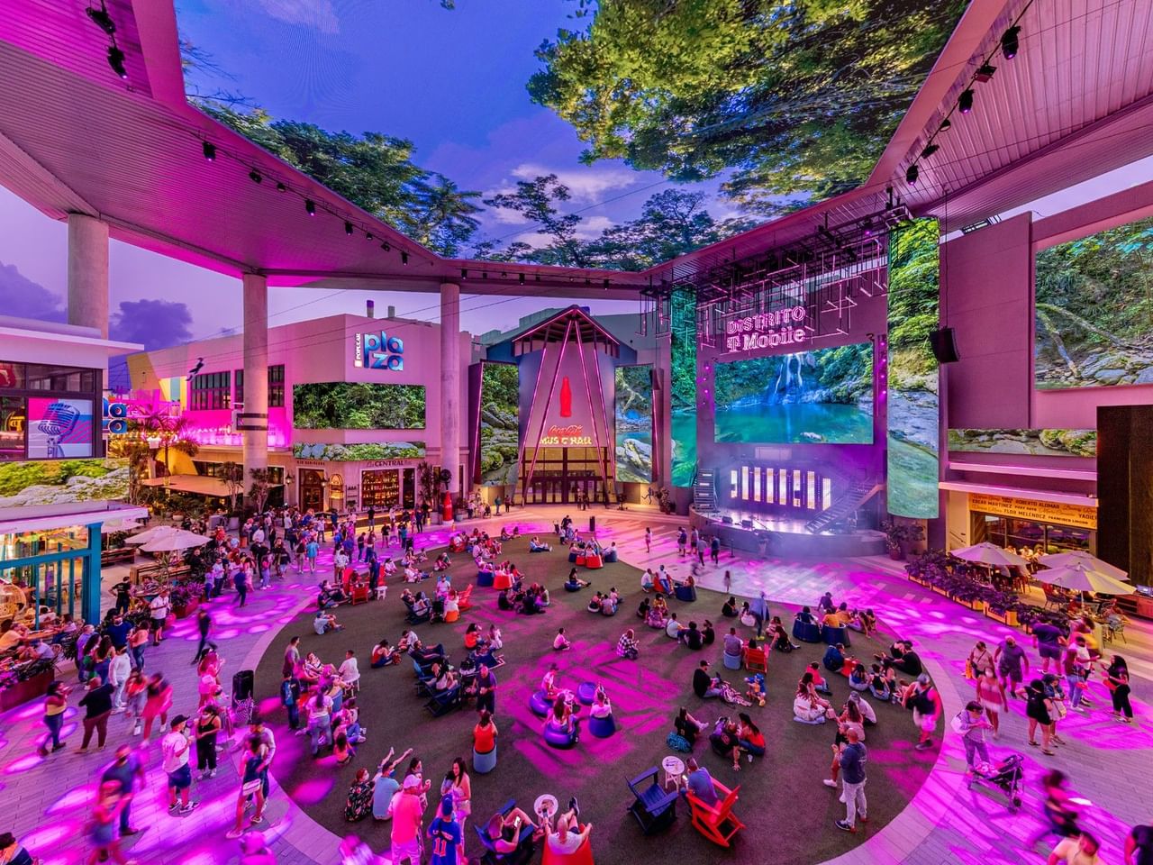 Crowded urban square with vibrant purple lighting and digital screens at Distrito T Mobile.