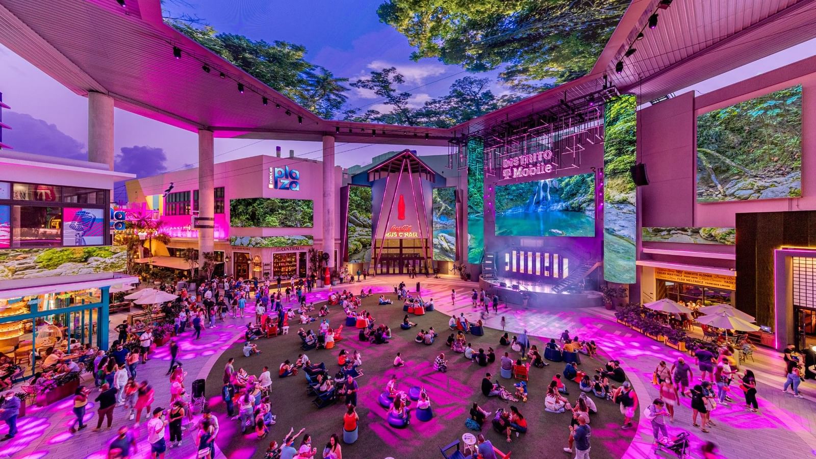 Vista aérea de la concurrida plaza Distrito T Mobile con luces de neón y gente disfrutando.