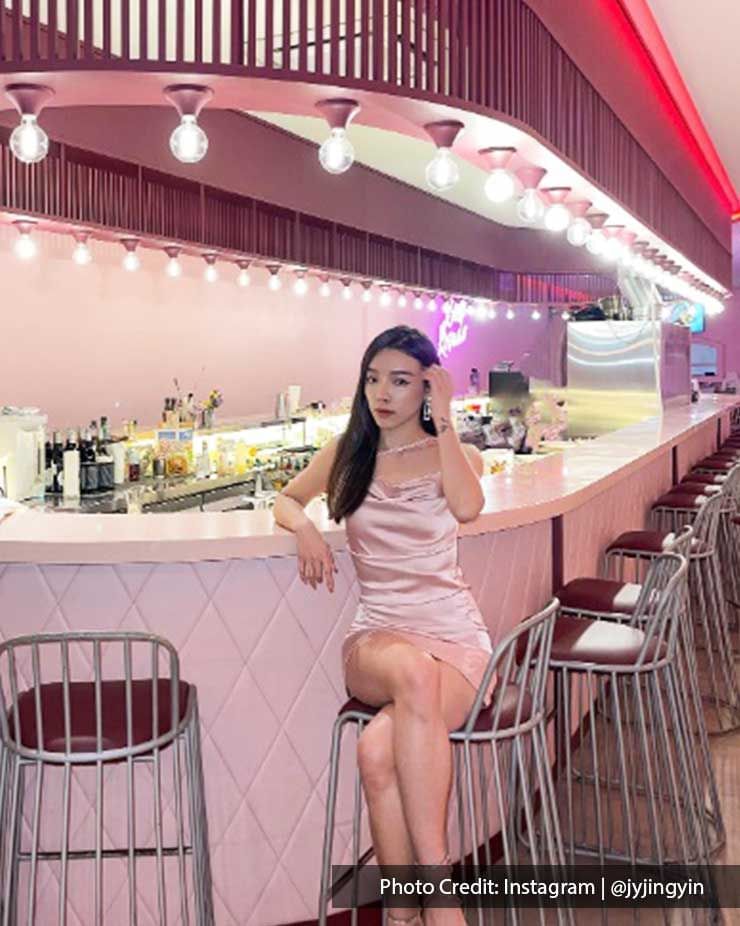 A lady styled in a pink dress seated on a bar stool at Beso Rosado - Lexis Suites Penang