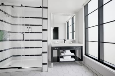 Sink with vanity mirror & shower area in 1 King Bed Deluxe Corner Room at Godfrey Hotel Detroit