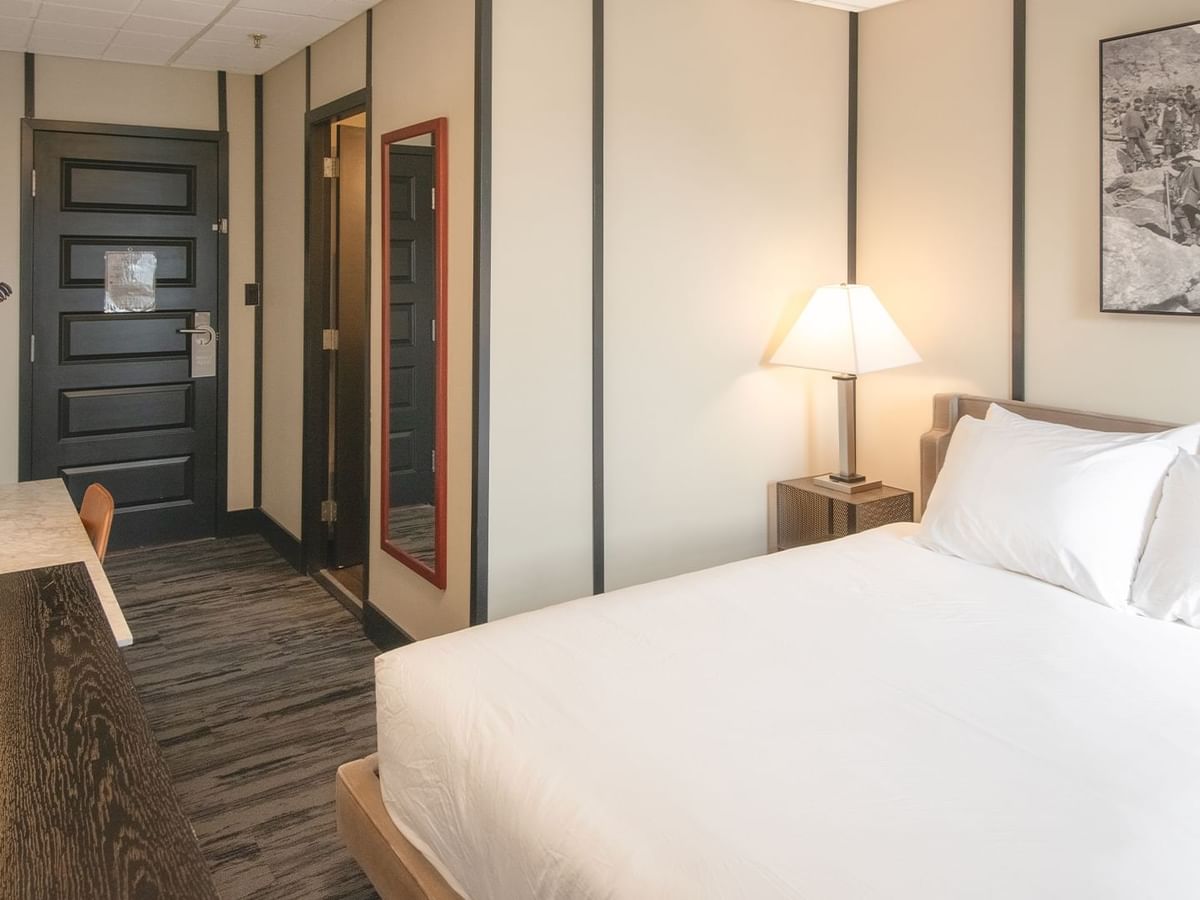 Hotel room with queen bed, night stand, lamp, and table