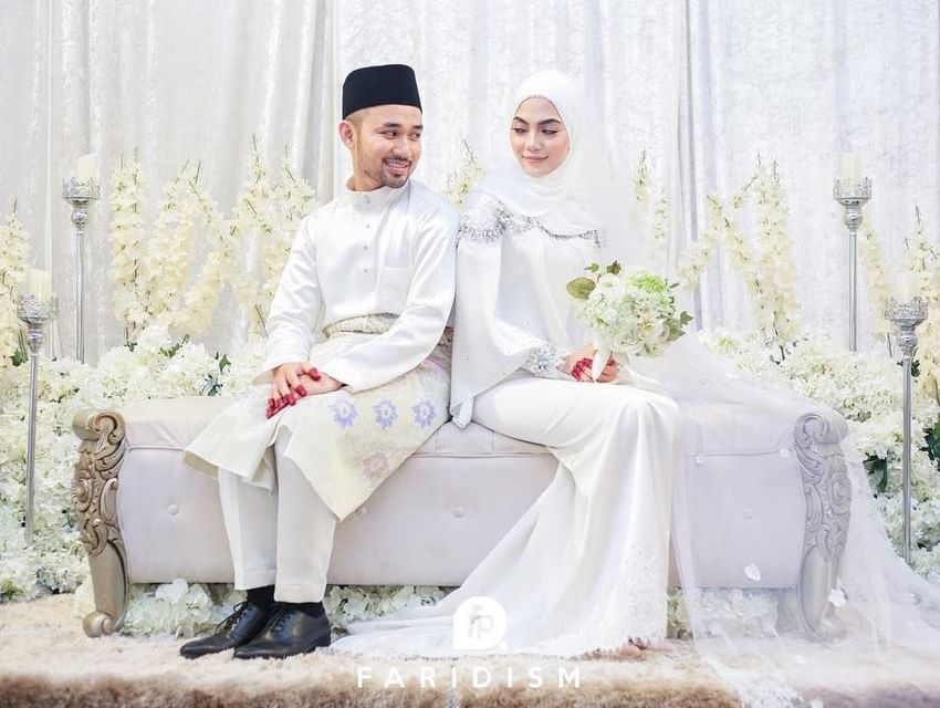 Wedded couple in traditional attire sitting on a couch at Hotel Maya Kuala Lumpur City Centre