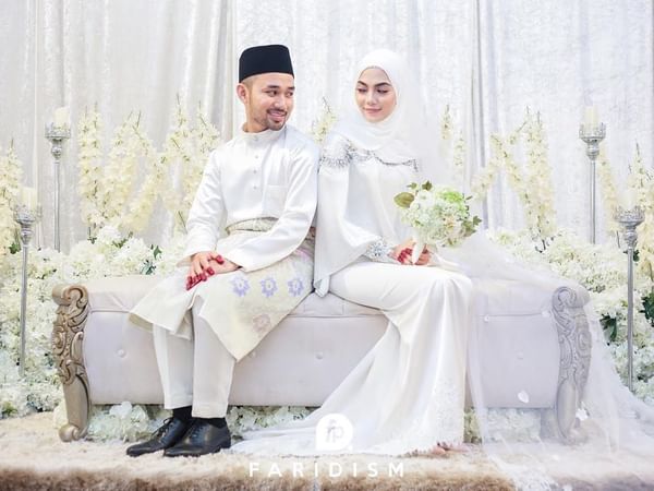 Wedded couple in traditional attire sitting on a couch at Hotel Maya Kuala Lumpur City Centre