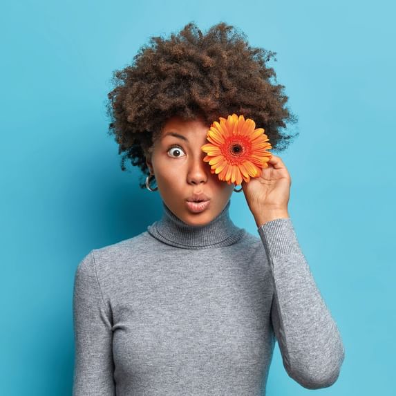 A woman holding a flower on her eye