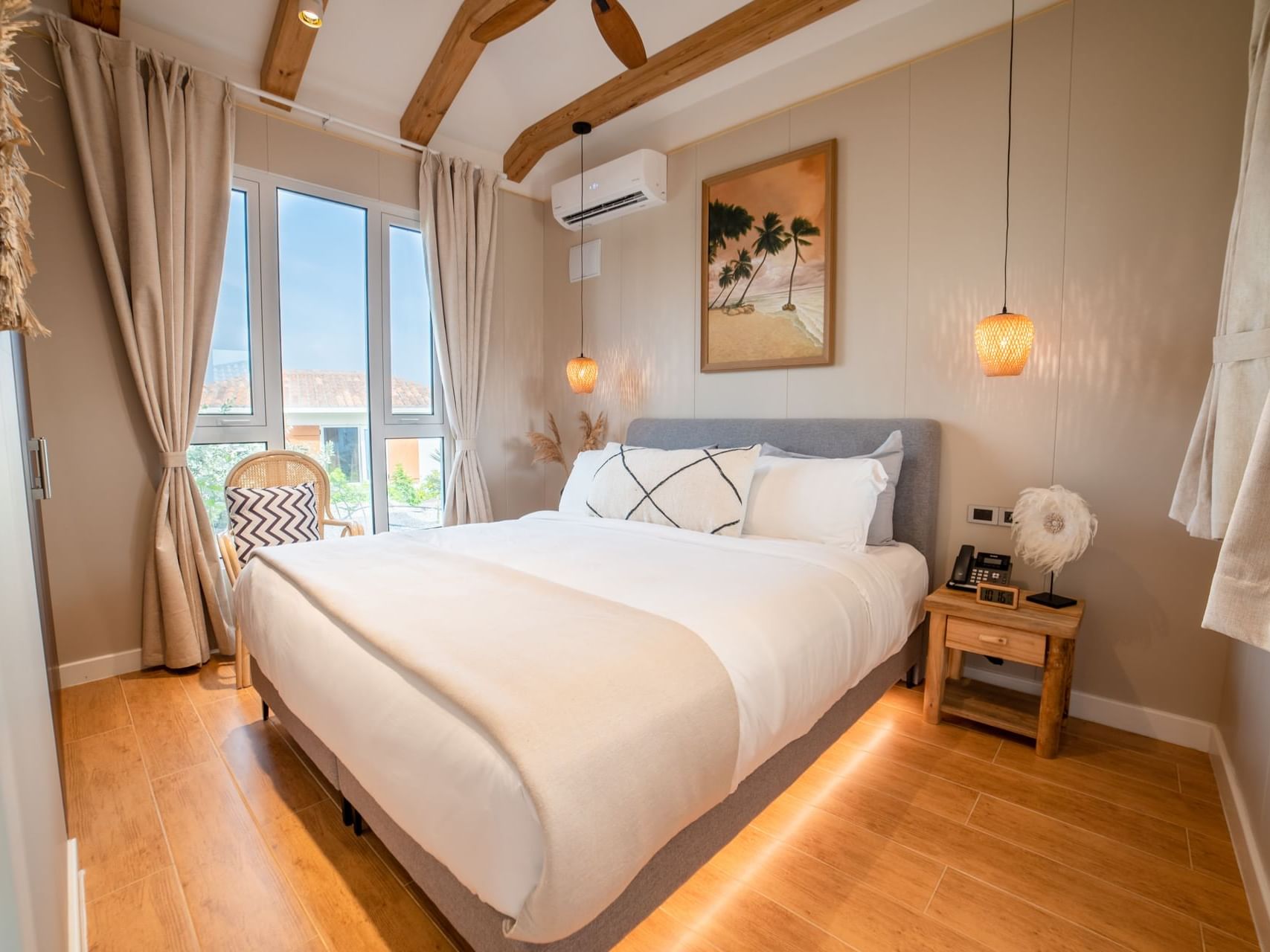 Nightstand and cozy chair by the bed in One-Bedroom Cottage with wooden floor at Golden Rock Resort