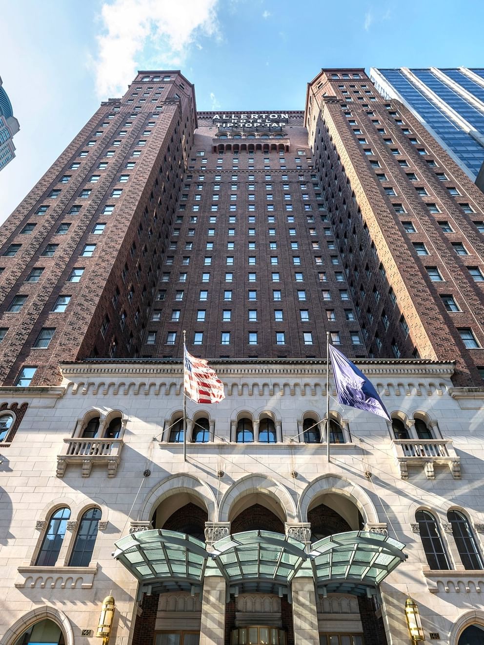 Tall building with many windows and two flags at Warwick Allerton - Chicago.