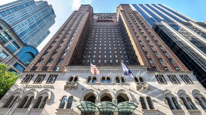 Exterior of the Warwick Allerton Chicago, featuring grand entryways by tall, surrounding buildings