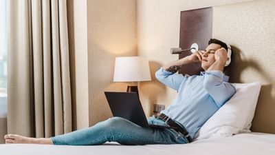 Person reclining on a bed with a laptop and listening to music at Polonia Palace Hotel