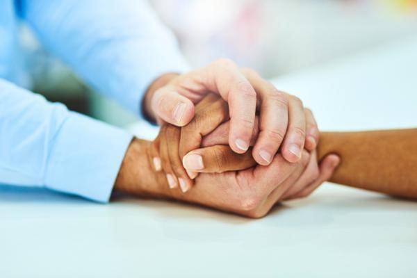 People holding hands as they try to help each other grieve
