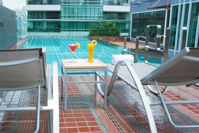 Two juice glasses & Bath towels by the pool at Amora Neoluxe Hotel Bangkok