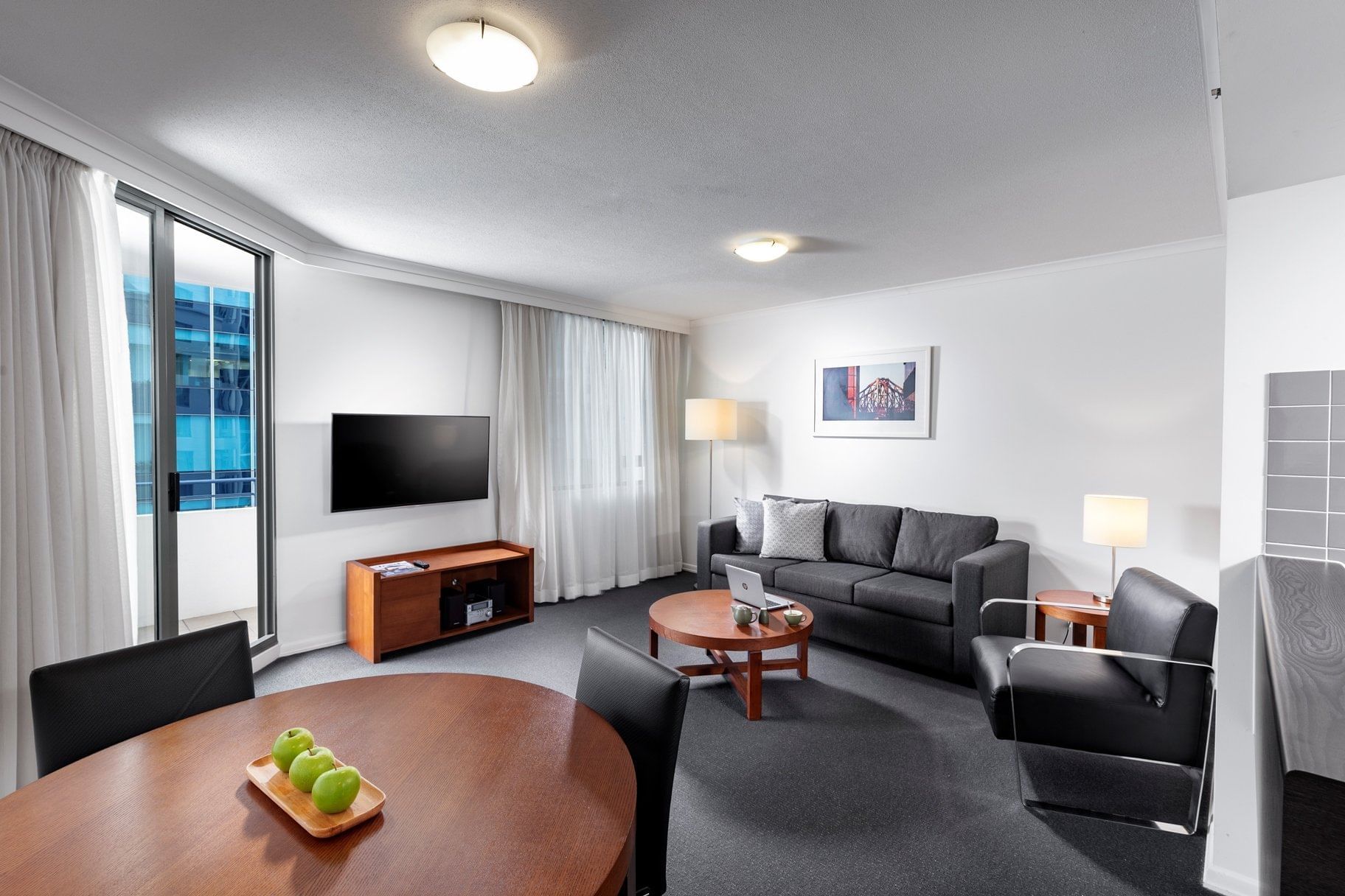 One Bedroom Apartment living area with a sofa, dining table, a TV, and floor-to-ceiling balcony door at The Sebel Brisbane