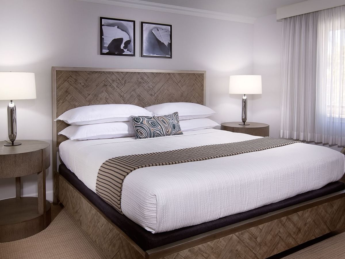 A hotel room with a large bed, two nightstands with lamps, and framed art on the wall.