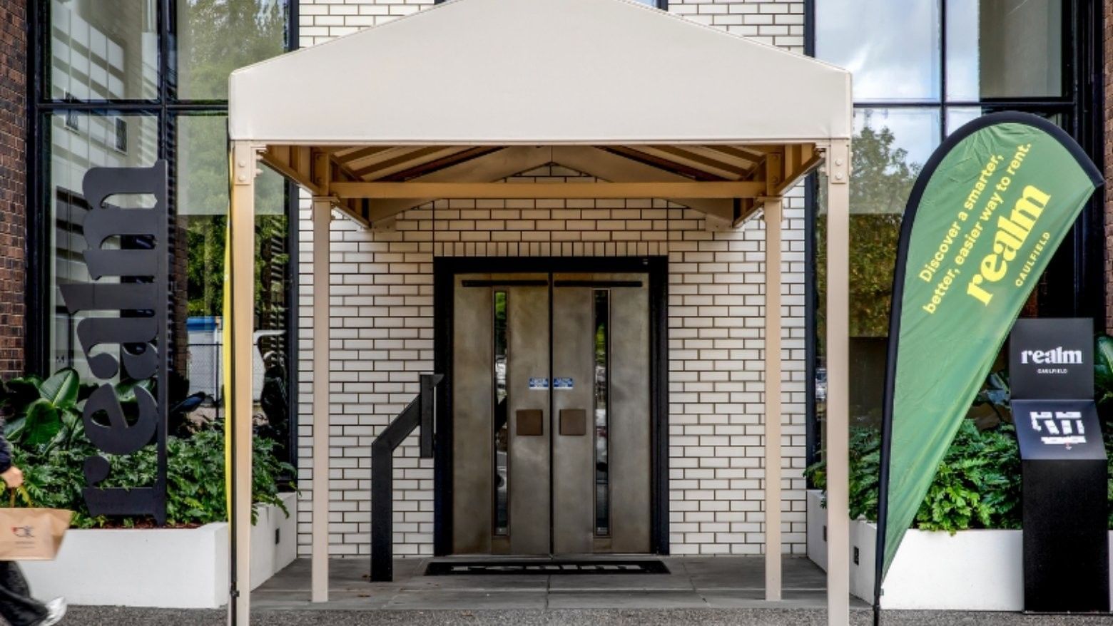 Entrance to a building with a canopy, double doors, and a green banner reading 