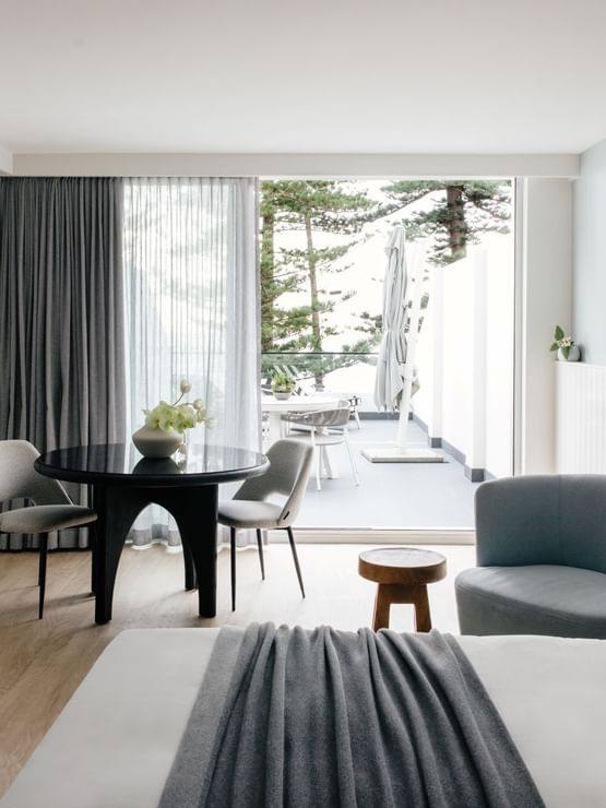 Wellness Two Bedroom Suite at Elysium Hotels dining table and chairs beside a balcony framed by tall pine trees
