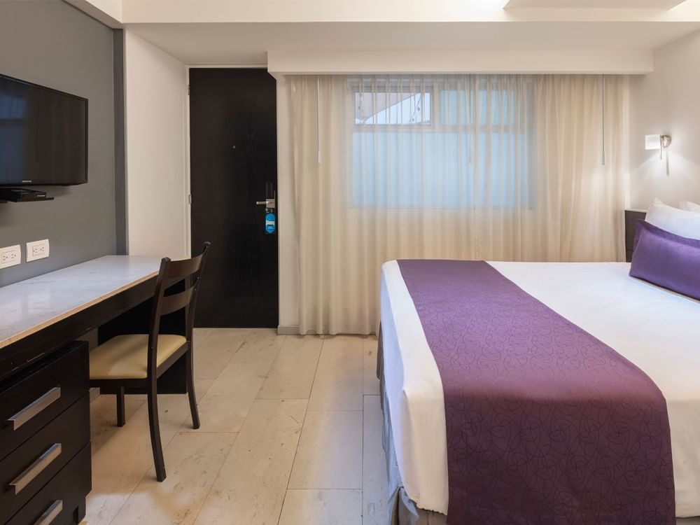 Cozy queen bed and TV with working area in Standard Queen Room at Gamma Hotels