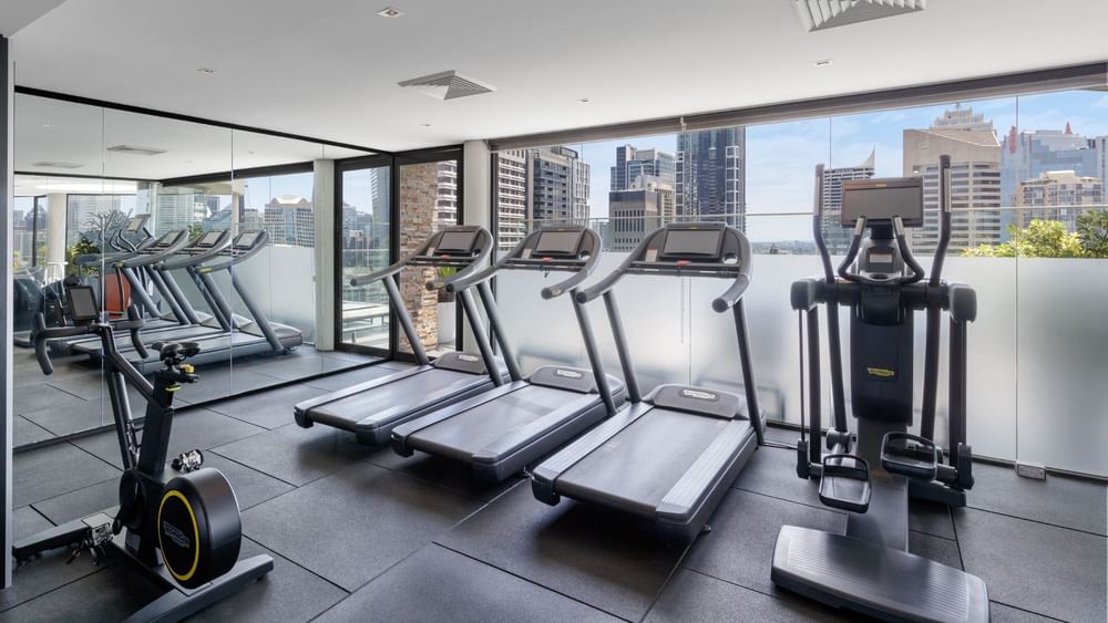 Fitness Centre with exercise machines and a view of the city at Pullman Sydney Hyde Park