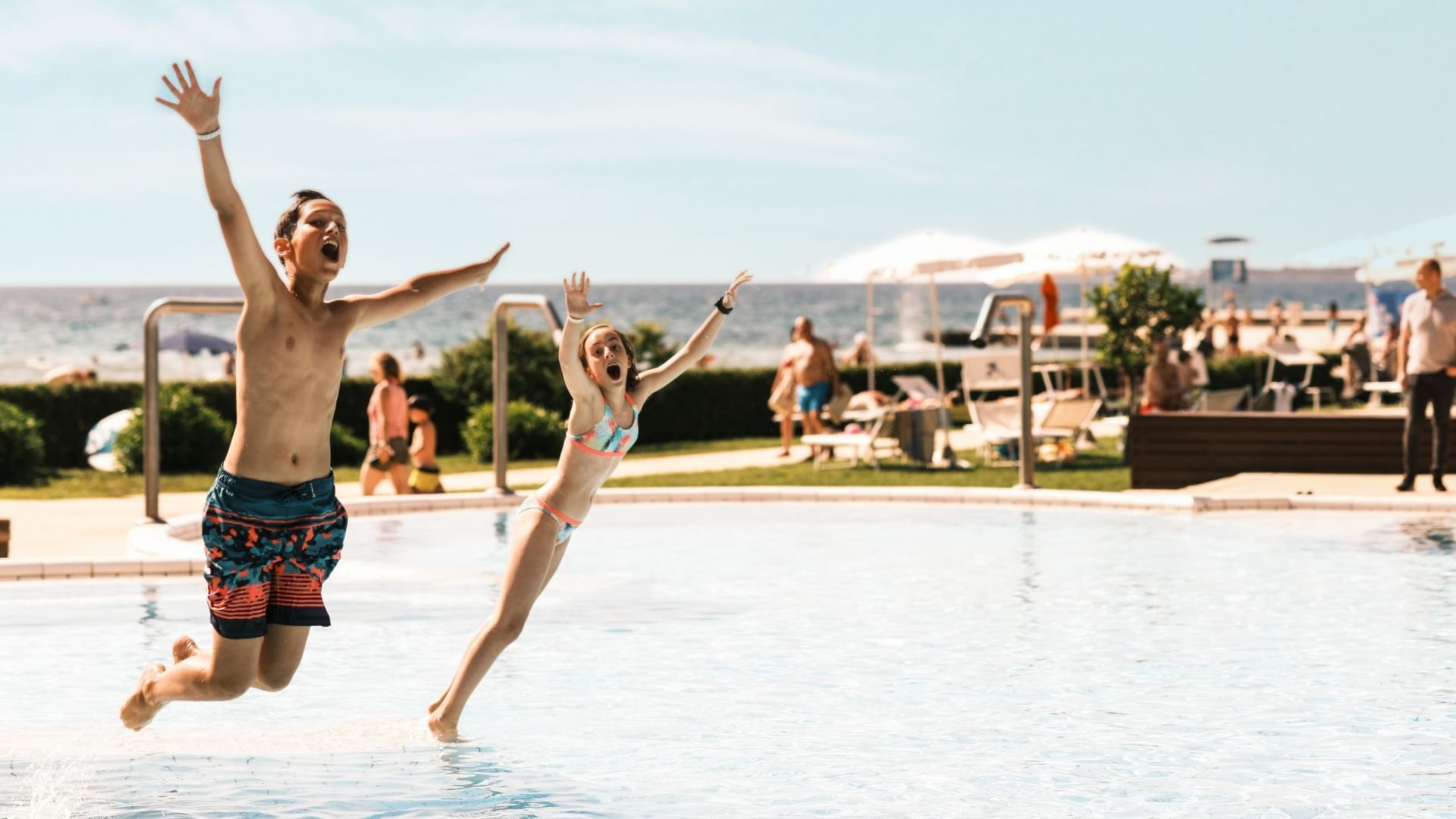 Two children jumping into a swimming pool on a sunny day at Falkensteiner Club Funimation Borik